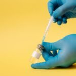 Close-up of gloved hands holding syringe and vial for vaccination.
