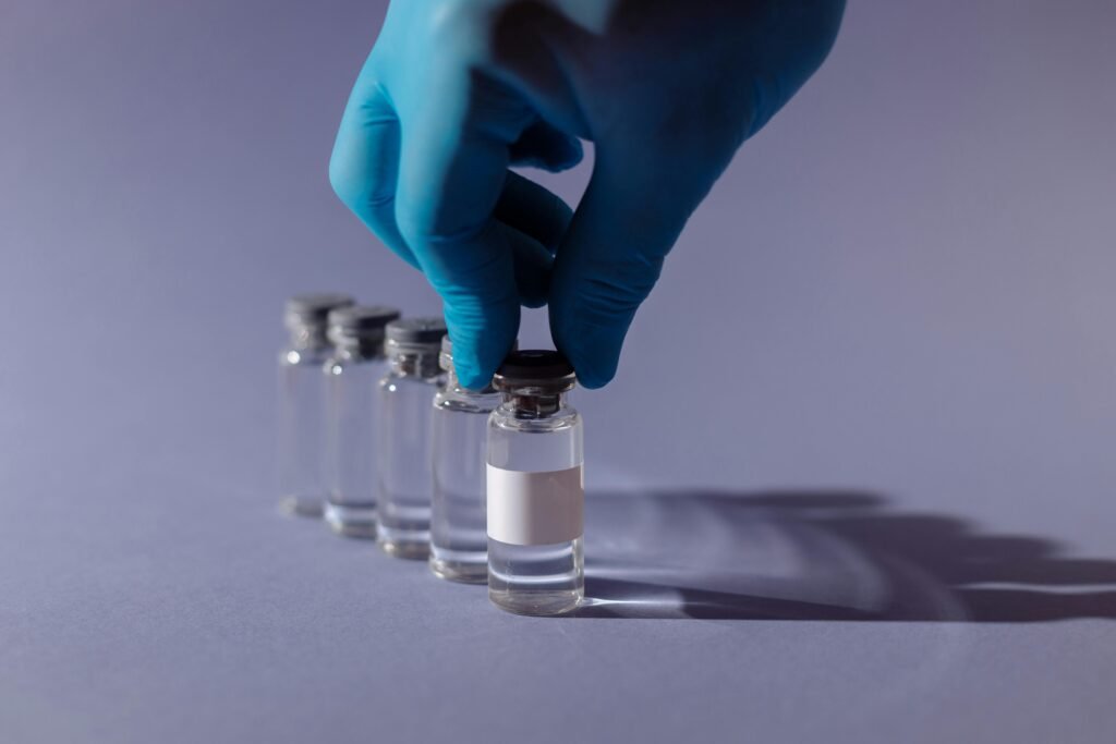 Healthcare worker with gloves handling vaccine vials in a sterile environment.
